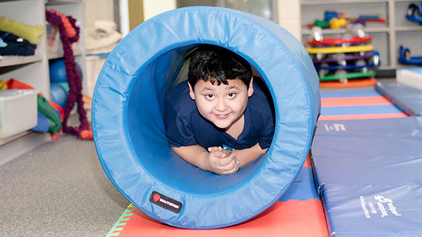 Young boy smiling in classroom inside a fun tube