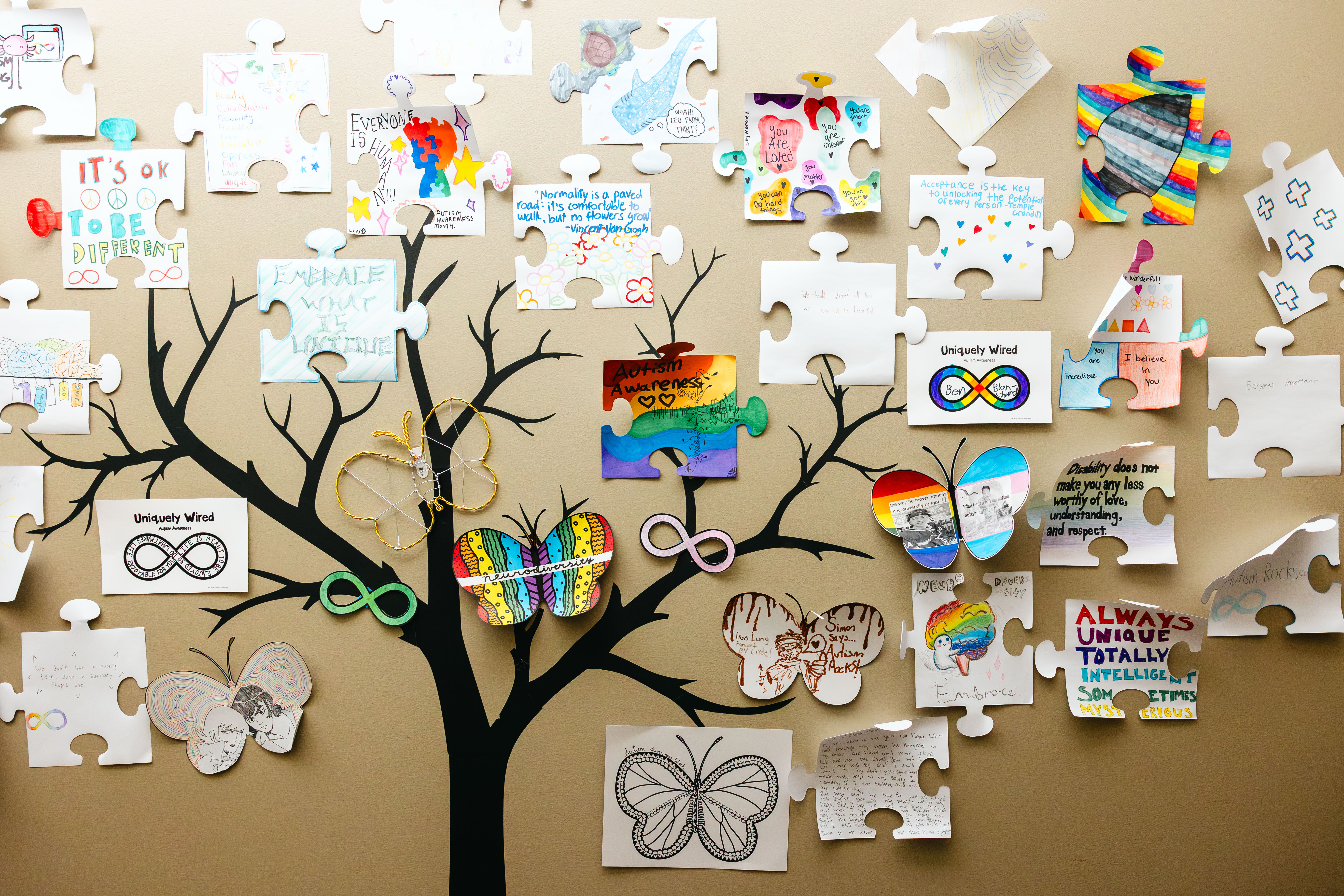 Student-created autism awareness artwork and puzzle pieces displayed on a wall at NewHope Academy.