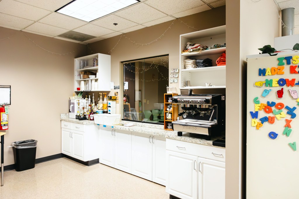 Student learning cafe with espresso machine, beverage supplies, and kitchen workspace