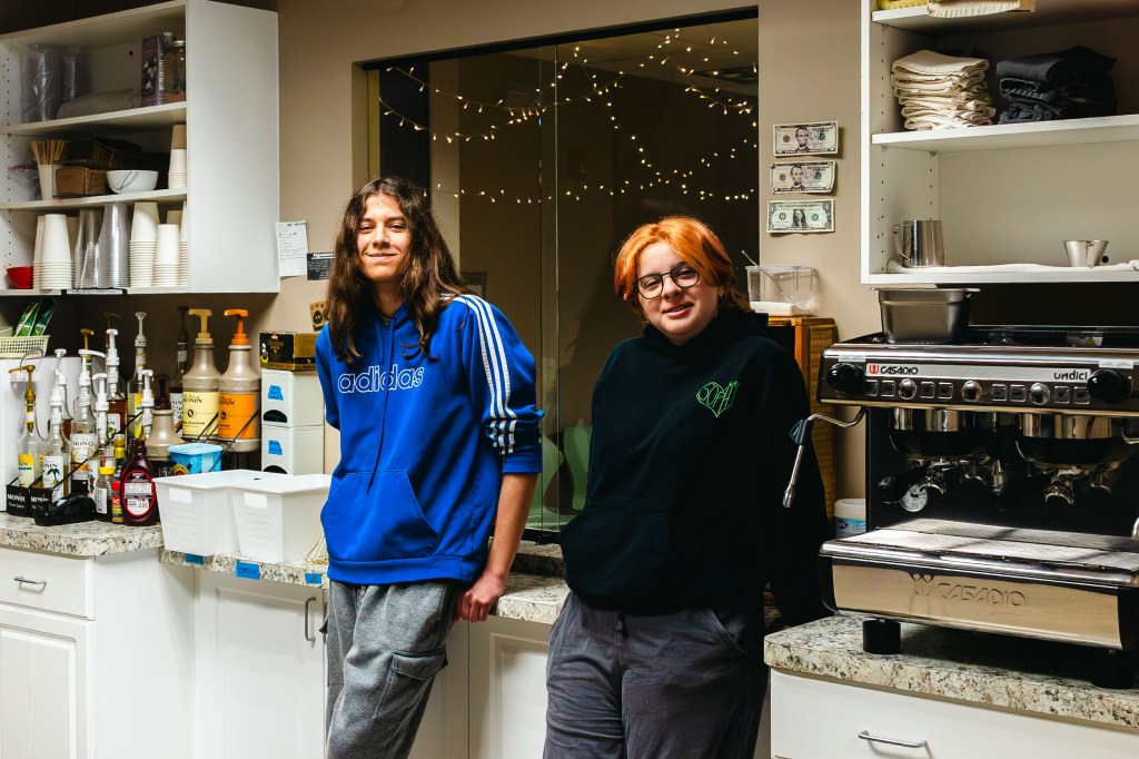 Two NewHope Academy students standing in the student cafe beside an espresso machine