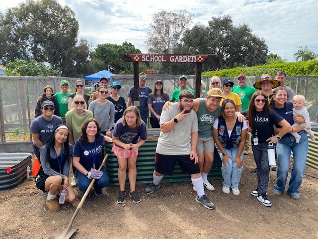 Sierra School of San Diego students, staff, and volunteers from Blue Shield of California gather under the garden arbor, celebrating teamwork in the sensory garden.