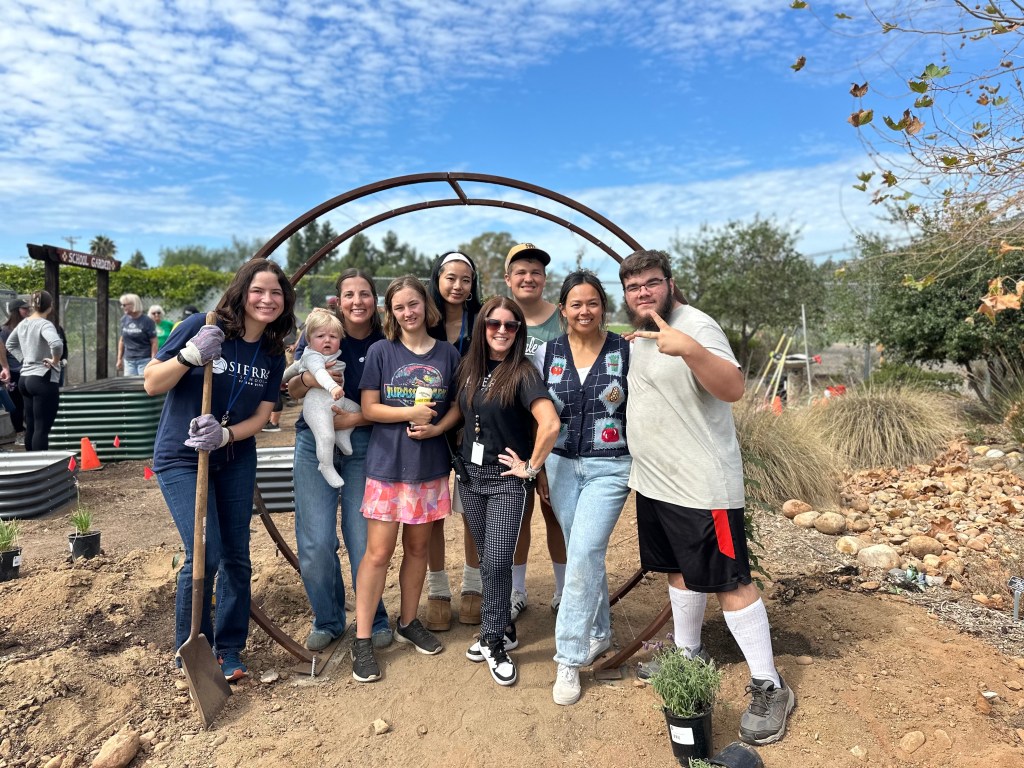 Large group of Sierra School of San Diego students, staff, and Blue Shield volunteers pose at the entrance of the school garden after completing the sensory garden planting event.