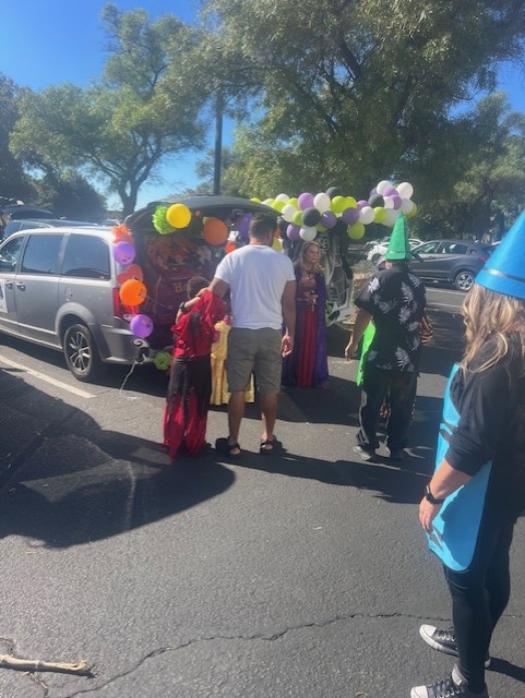 Attendees interacting with the Hocus Pocus-themed car and witch-costumed host