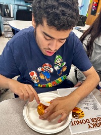 Students using fine motor skills to decorate donuts during therapy session.