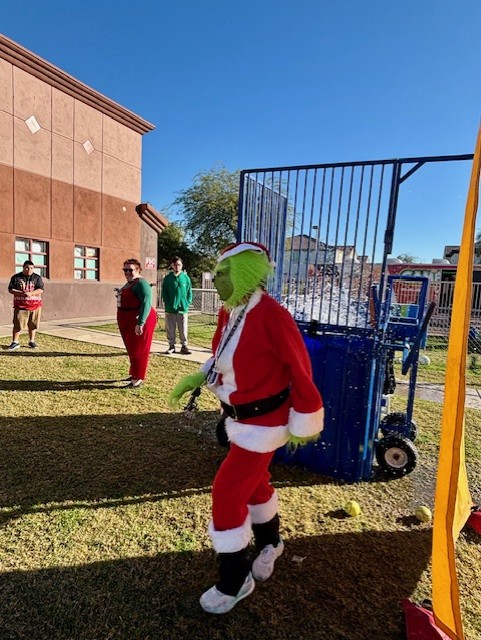Miembro del personal disfrazado de Grinch celebrando con los estudiantes durante el Carnaval de Invierno de Sierra Gilbert.