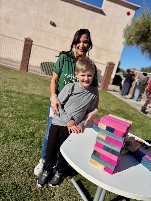 Miembros del personal y estudiantes posando juntos junto a un gran juego tipo Jenga en el Carnaval de Invierno.