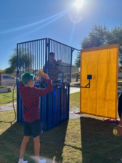 Un estudiante lanza una pelota hacia el objetivo del tanque de agua durante la celebración escolar.
