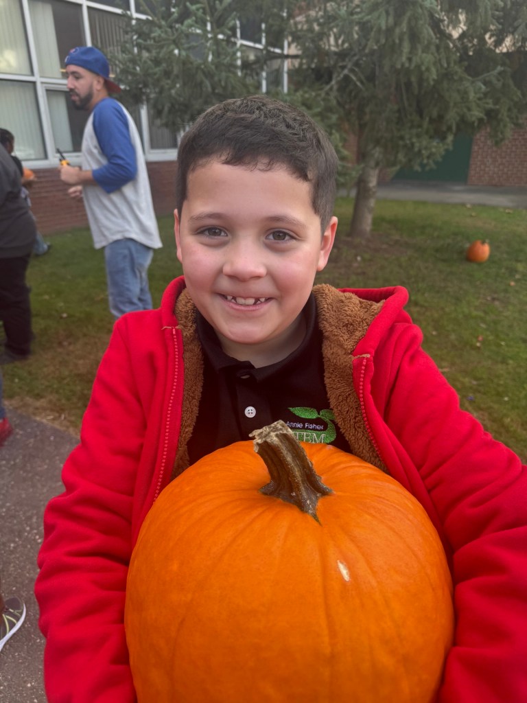 Sebastian smiling with a pumpkin during a High Road School activity
