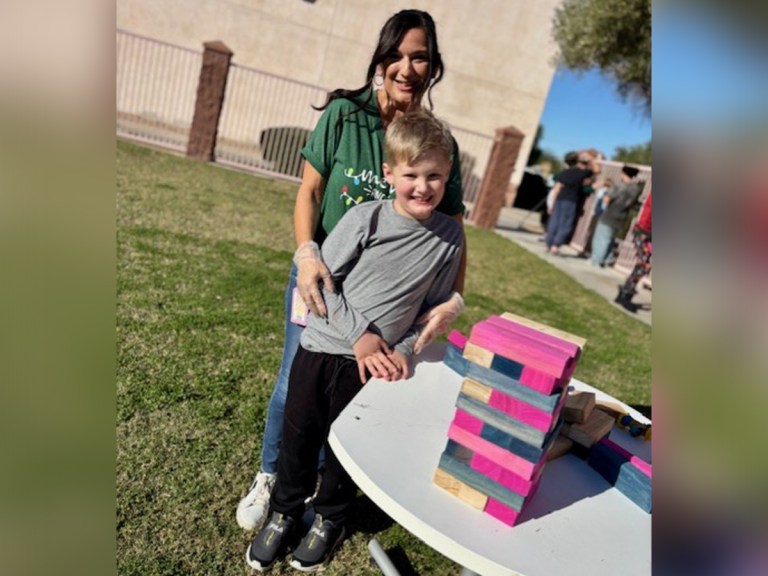 Staff member and student posing together near a large Jenga style game at the Winter Carnival