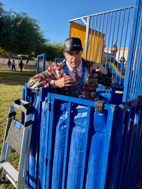 El director de la escuela Sierra Gilbert sentado dentro del tanque de agua con un traje festivo después de haber sido salpicado.