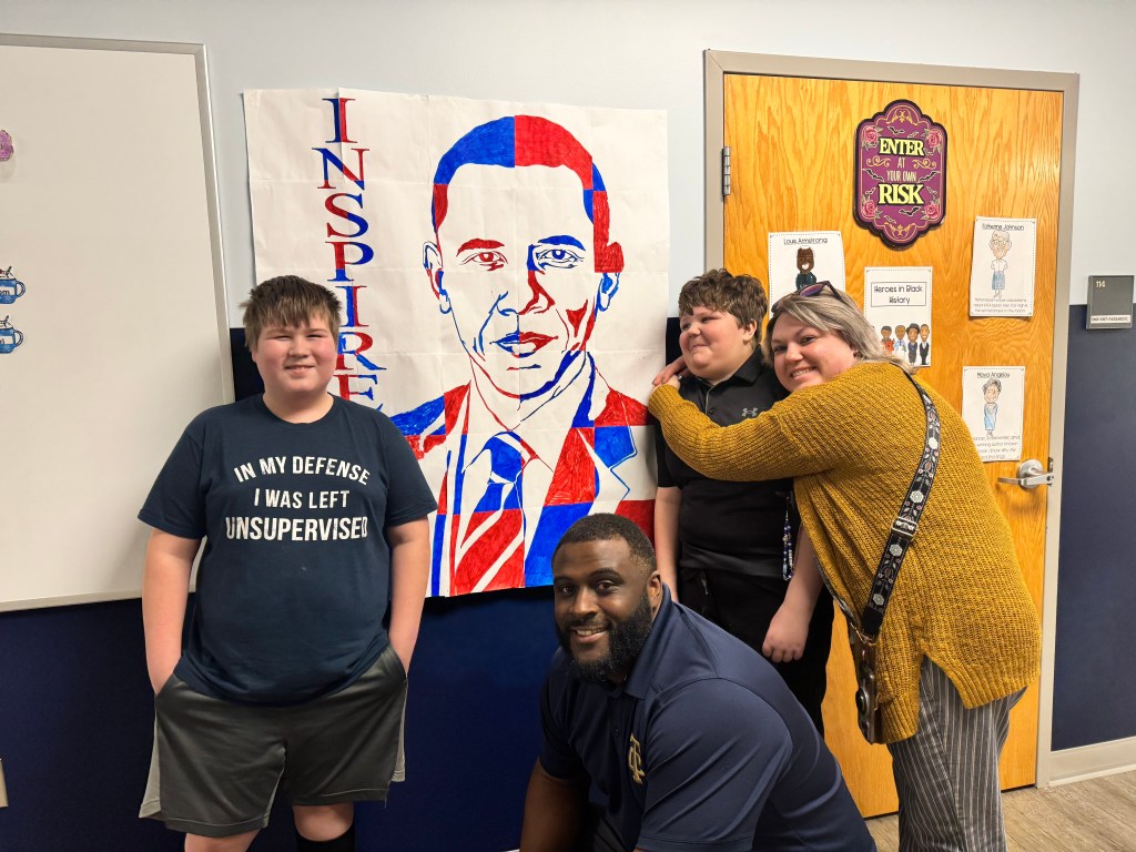 Students and staff with student-created Barack Obama poster during Black History Month learning activities