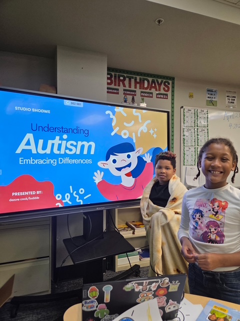 Alumnos de pie en un aula frente a una pantalla en la que se lee «Comprender el autismo, aceptar las diferencias» durante una actividad de sensibilización sobre el autismo