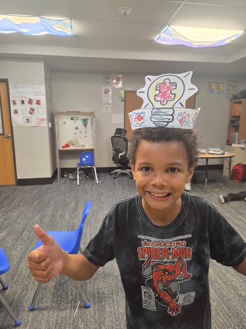 Un alumno sonriente con un gorro de papel de «pensador» durante una clase de sensibilización sobre el autismo en la Sierra School del condado de Solano