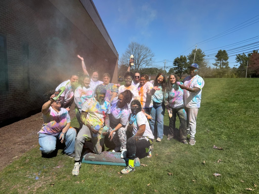 Staff group smiling covered in colorful powder during Autism Awareness event