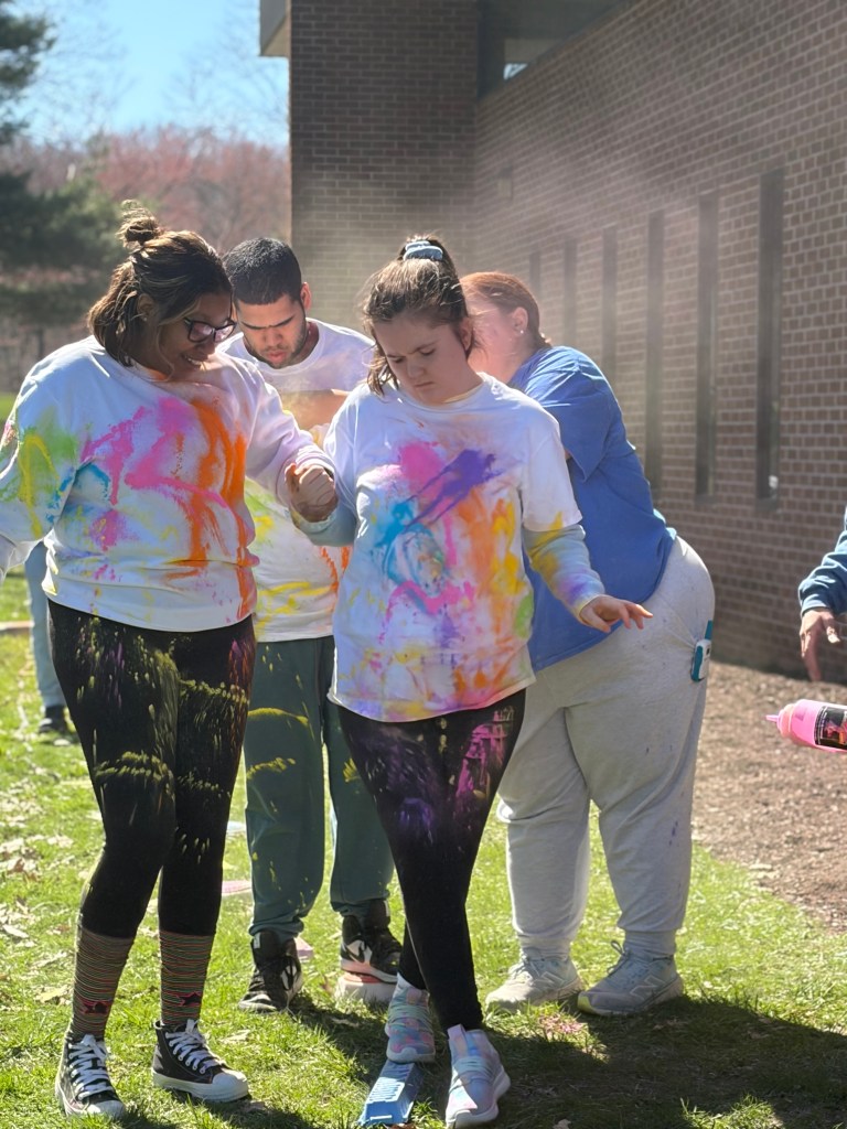 Staff holding student’s hand while walking through colorful obstacle course activity