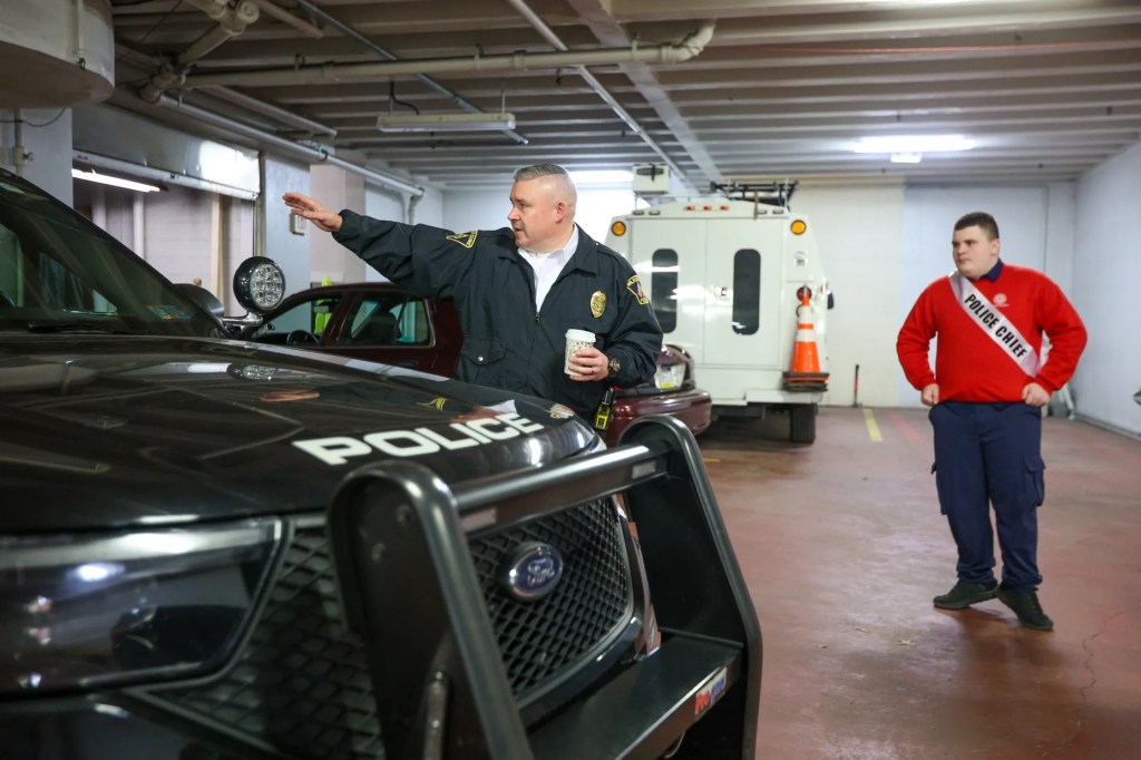 Cathy Payne, secretaria del Ayuntamiento de Wilkes-Barre, ayuda al miembro honorario del Ayuntamiento Jaxon Gillam a colocarse la banda durante un acto celebrado con motivo del Mes de Concienciación sobre el Autismo en el Ayuntamiento de Wilkes-Barre el viernes 10 de abril de 2026.