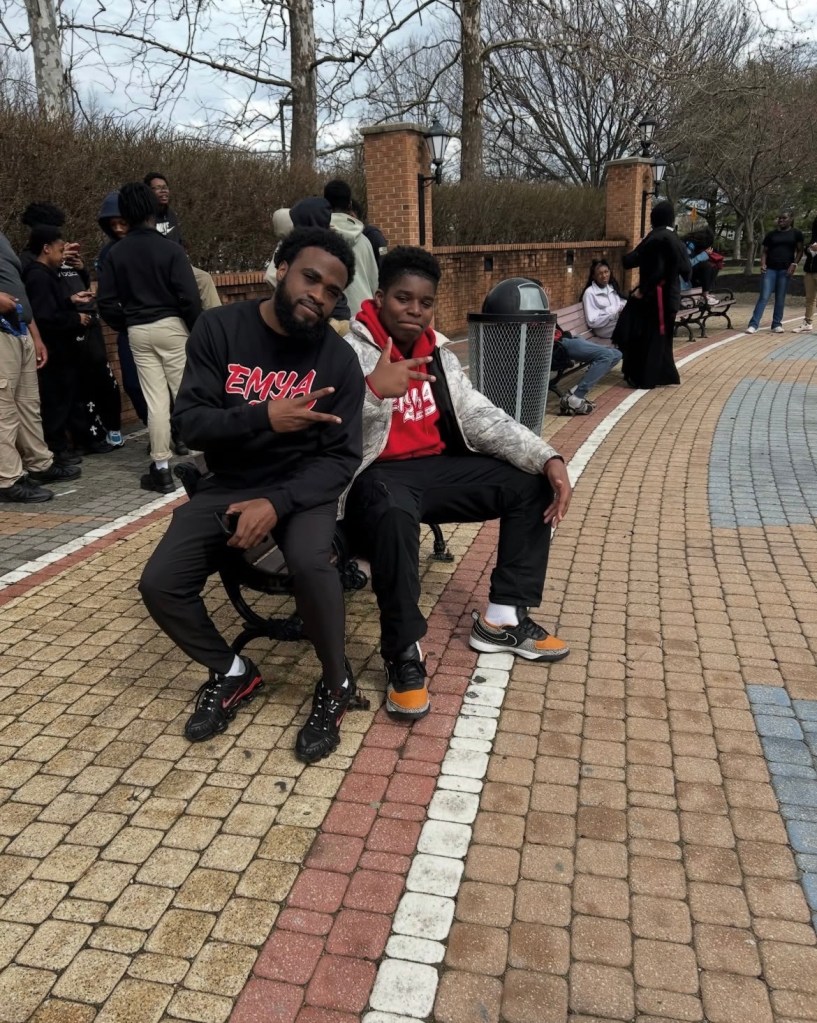 Un estudiante y un miembro del personal de Excel se sientan en un banco del campus de la Universidad Estatal de Delaware, sonriendo y posando durante una visita guiada por la universidad
