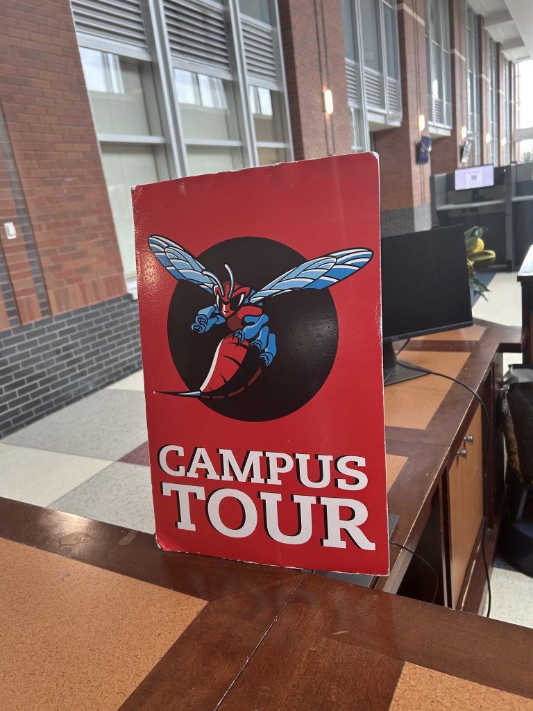 Primer plano de un cartel de la visita guiada al campus de la Universidad Estatal de Delaware, en el que aparecen la mascota, un avispón, y los colores rojo y azul