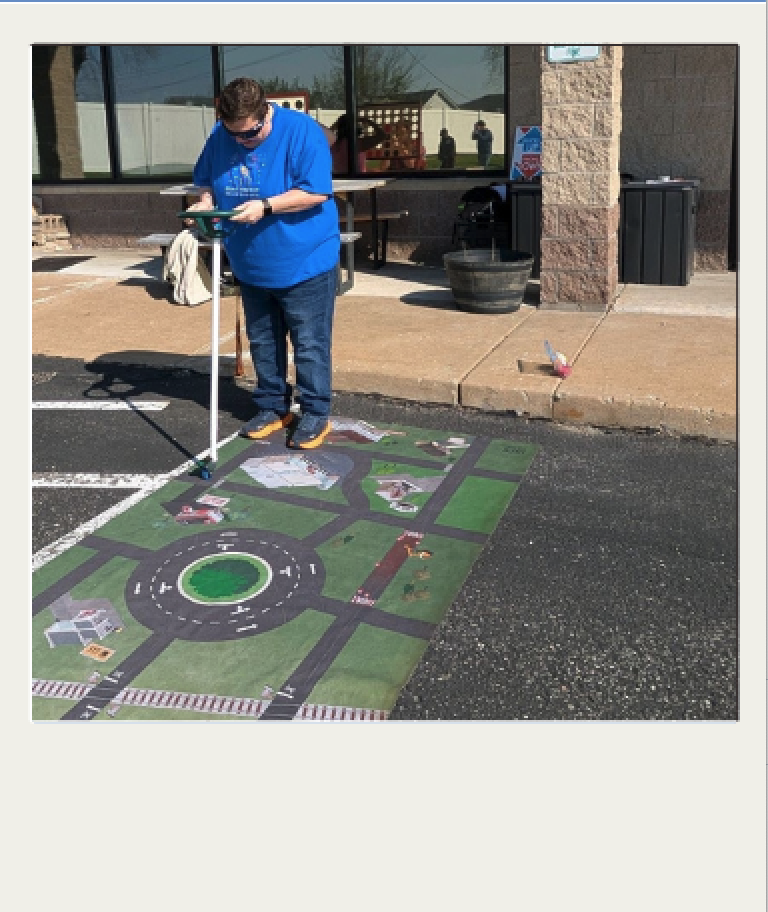 Personal que supervisa una simulación de conducción segura en una alfombra de obstáculos con motivos viales