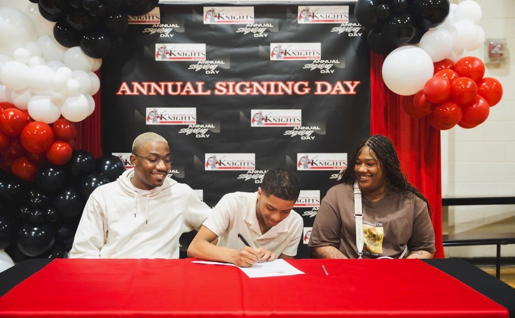 Un alumno firma su compromiso durante la jornada de firmas en la Excel Middle Years Academy, con el apoyo de su familia