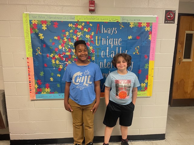 Students posing in front of an autism awareness sign at Delco Academy during World Autism Month
