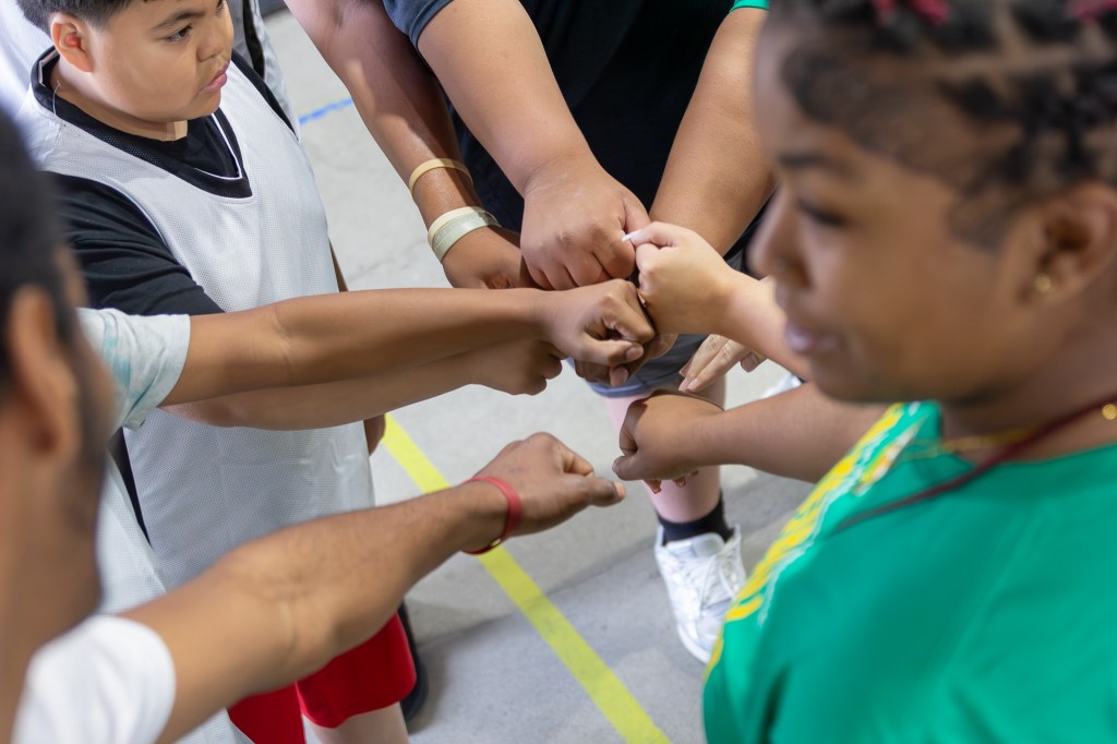 Sierra Schools team gathers with hands in the center during a pregame huddle on the court
