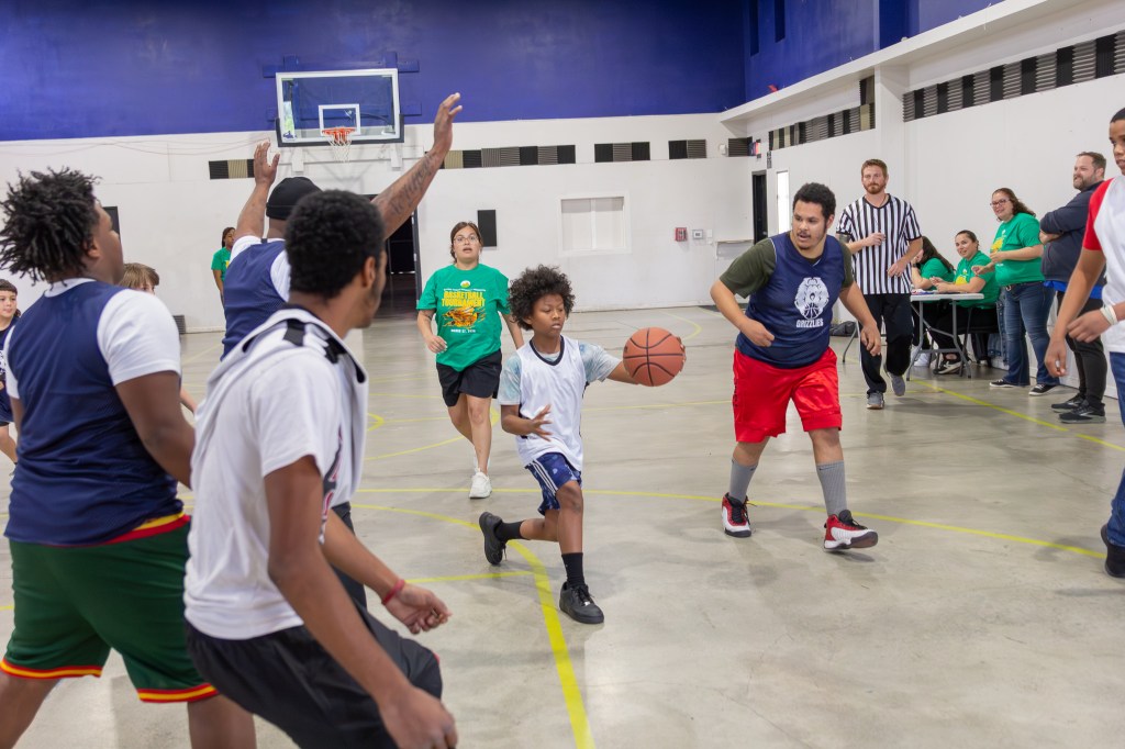 Student dribbles the basketball while navigating defenders during the Sierra Schools tournament game