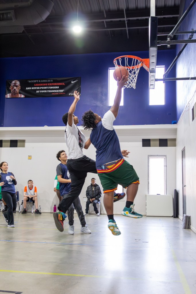 Student goes up for a layup while another player attempts to block the shot during the game