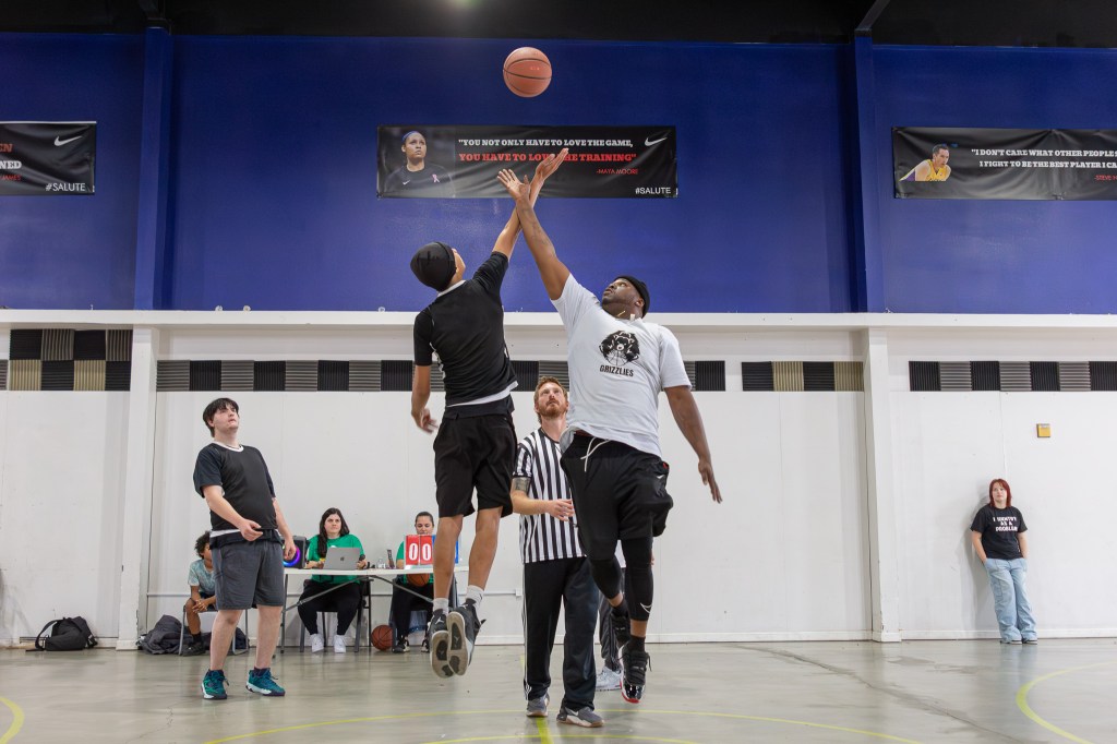 Referee tosses the ball for a jump ball as two students compete at center court during the tournament