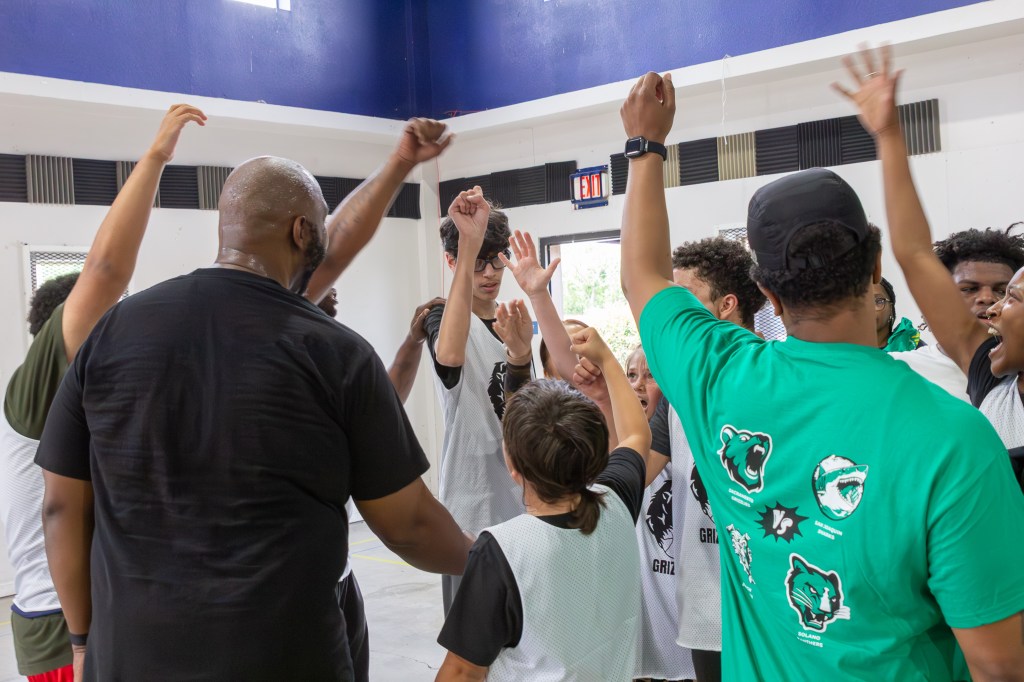 Sierra Schools students and staff gather in a team huddle raising their hands before the game