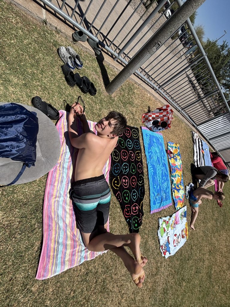 Student relaxing on a towel after splash pad play during PBIS reward outing