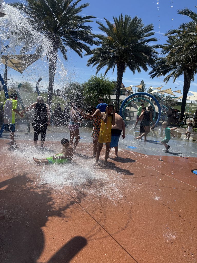 Students running and playing under water at splash pad during PBIS celebration