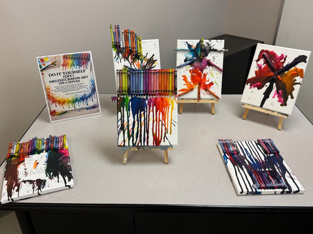 Melted crayon art canvases with vibrant colors created by students