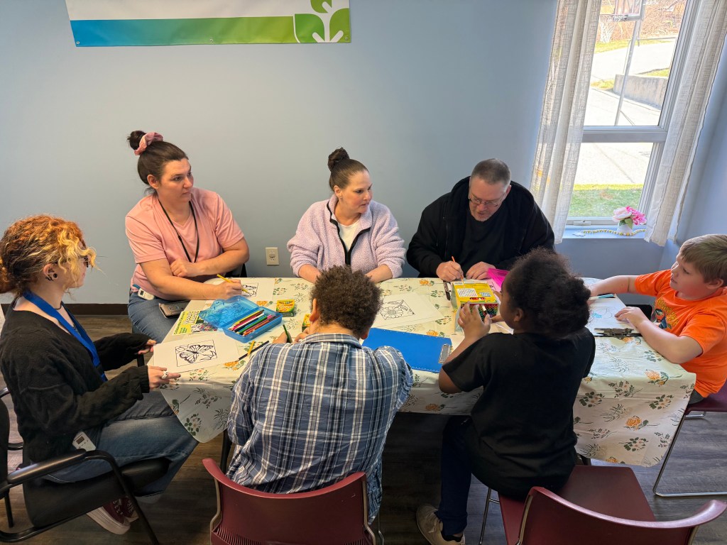 Students and staff working on art projects with colored pencils and paper