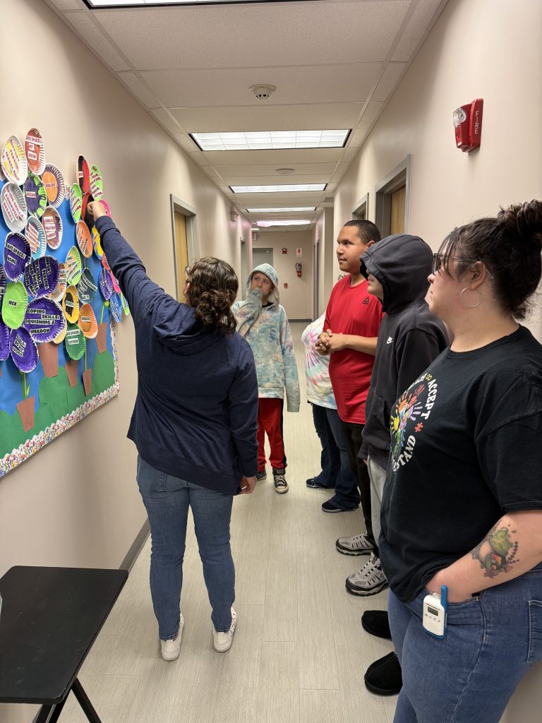 Students and staff viewing wall display of paper plate flowers and artwork