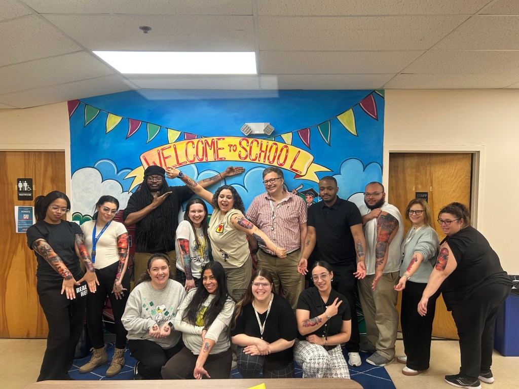 Staff group showing temporary tattoos during student fundraiser at High Road School