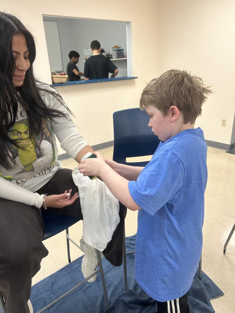 Student applying temporary tattoo to staff member during fundraiser activity