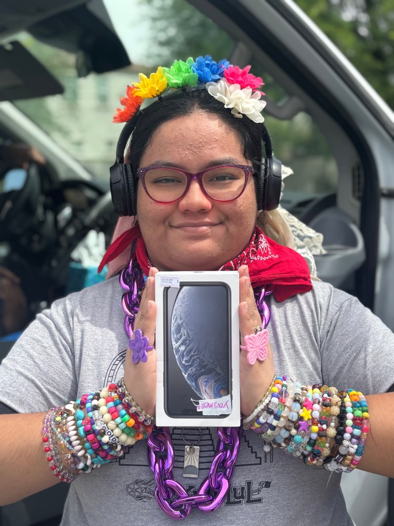 Yasmeen holding a new iPhone in original packaging after earning it through the CASE Cash program at Sierra School of Gilbert