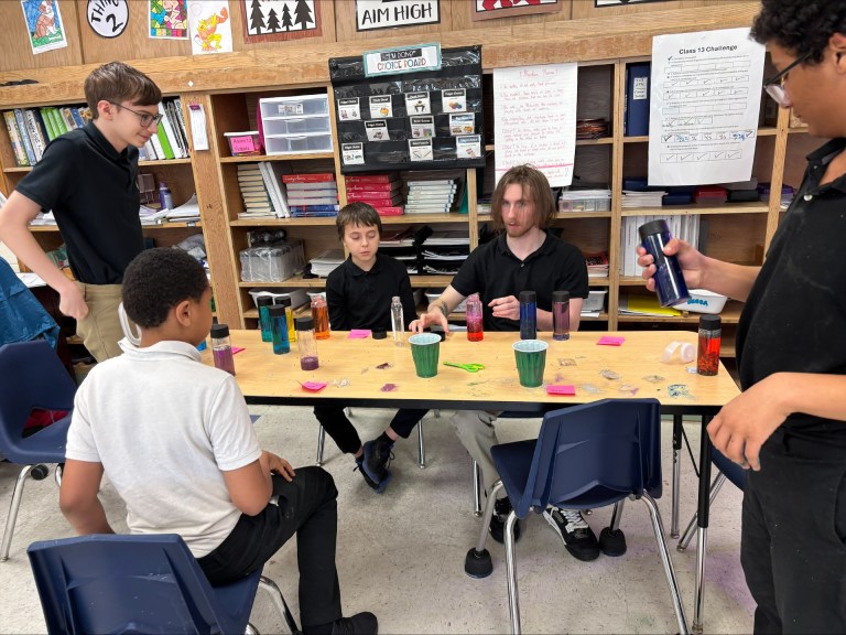 Un grupo de estudiantes que está creando proyectos de apoyo al autismo con botellas sensoriales, tijeras y materiales de manualidades