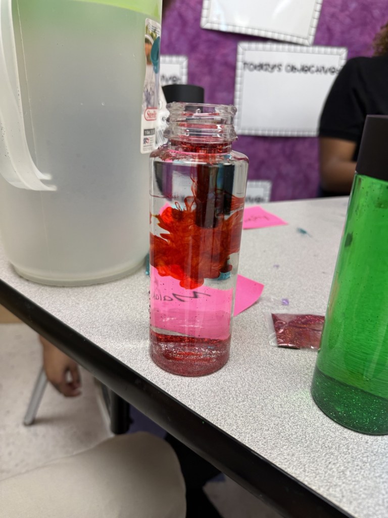 Primer plano de una botella sensorial con colorante rojo flotando en un líquido, como parte de un proyecto de apoyo al autismo