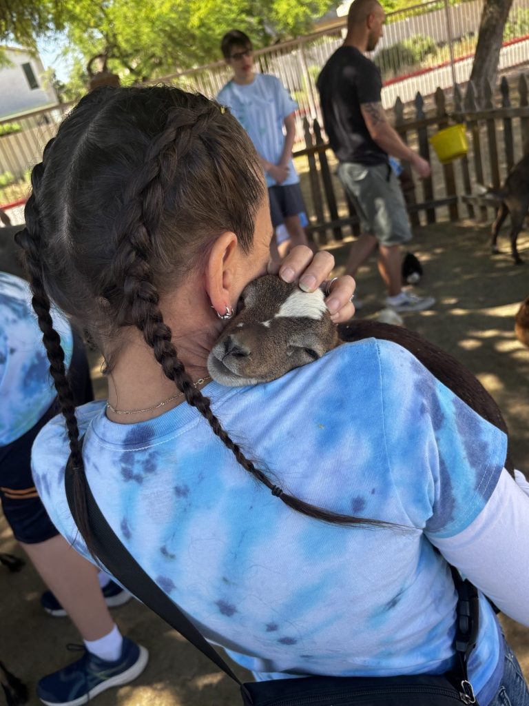 Un miembro del personal abraza con ternura a una cabrita en un acto de sensibilización sobre el autismo