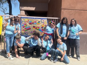 Grupo posando con un cartel que reza «Sé amable con todas las mentes» en un evento sobre el autismo