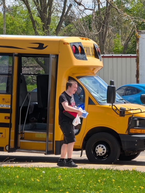 Un alumno junto a un autobús escolar, con unas bolsas en la mano, tras llegar al Northwest Center for Autism.