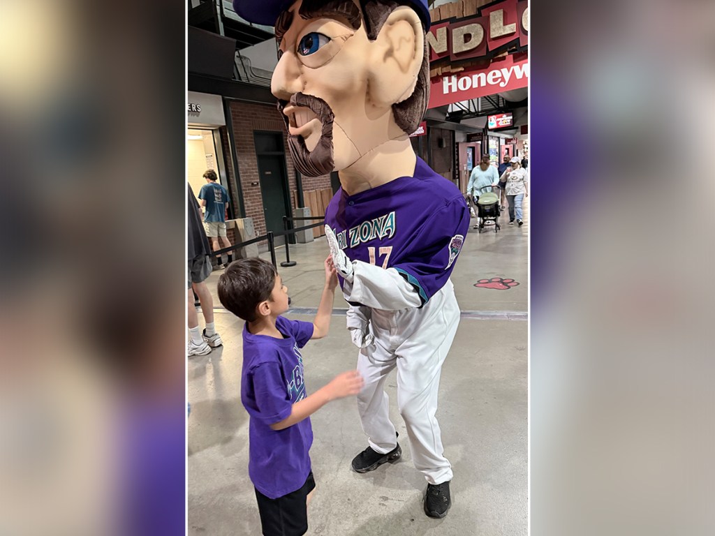Student gives a high five to an Arizona Diamondbacks mascot during Autism Acceptance Night activities.