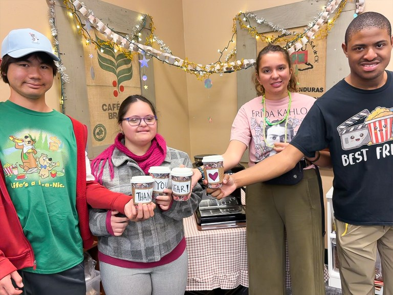 Students at Sierra School of San Diego hold coffee cups spelling out “Thank You NFAR” while celebrating support for the Coffee Corner vocational program.