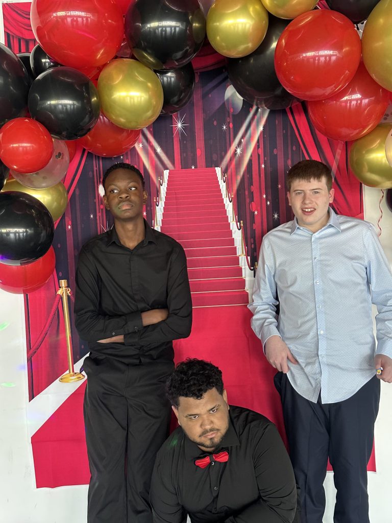 Estudiantes posando ante un fondo decorado al estilo de Hollywood para el baile de fin de curso