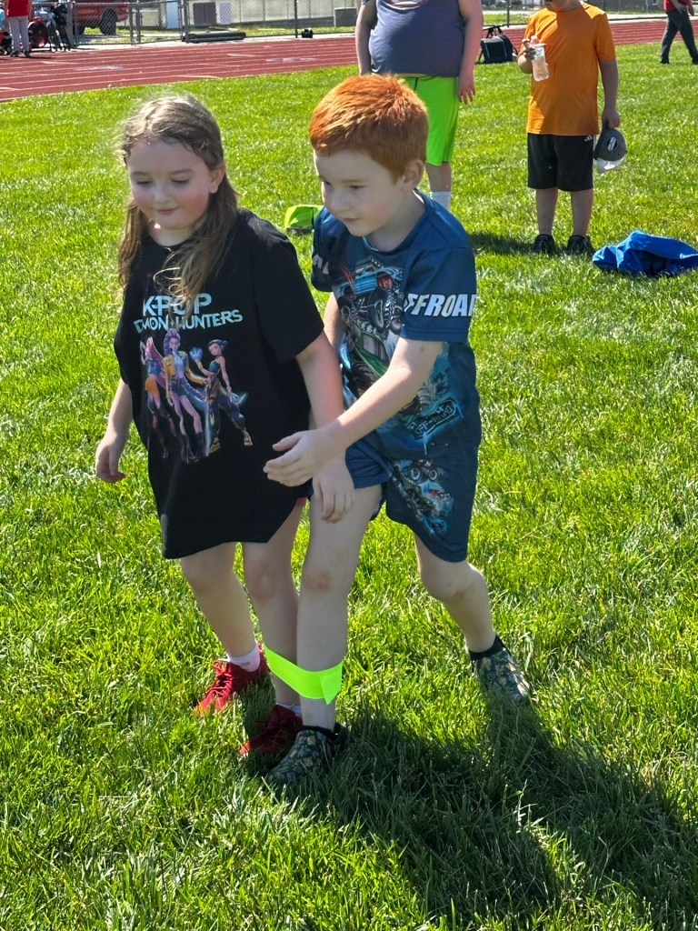 Two students working together during a three-leg race at Field Day
