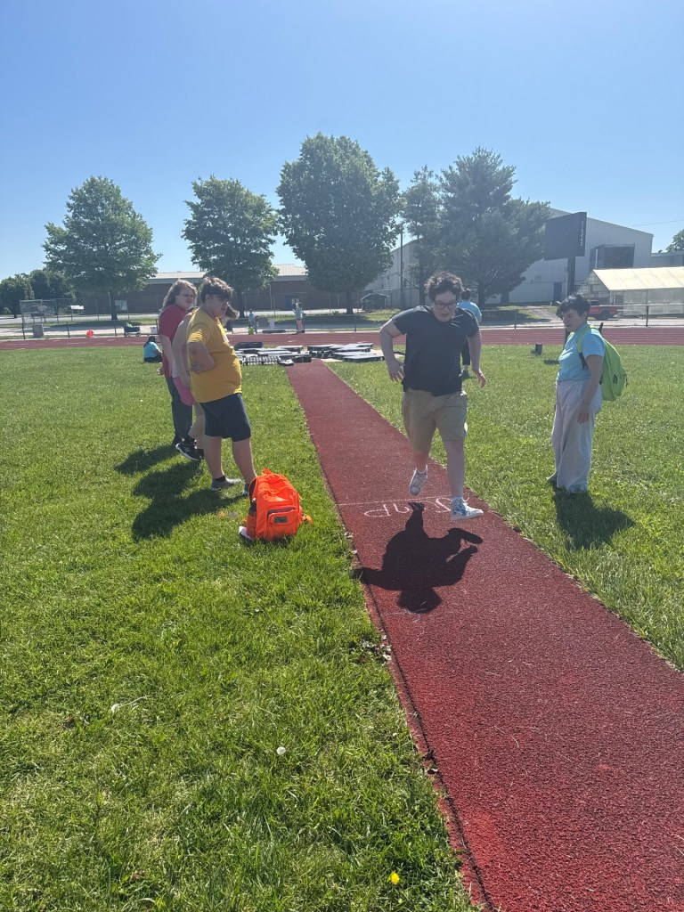 Student participating in long jump activities during High Road School Field Day