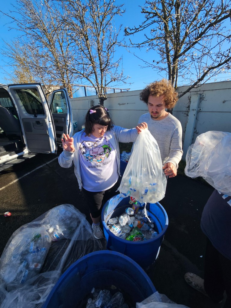 Students placing plastic items into a recycling bin during a school activity.