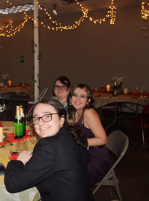Students dressed for prom smiling together at a decorated table during the NewHope Academy celebration.